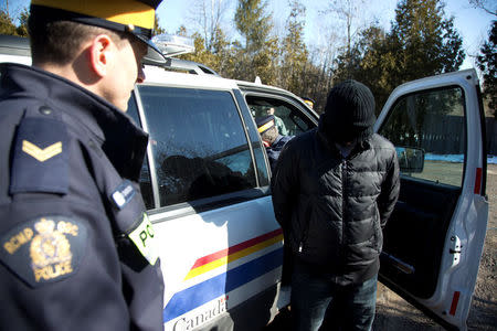 A family of four are taken into custody by Royal Canadian Mounted Police (RCMP) officers after crossing the U.S.-Canada border into Hemmingford, Quebec, Canada February 20, 2017. REUTERS/Christinne Muschi