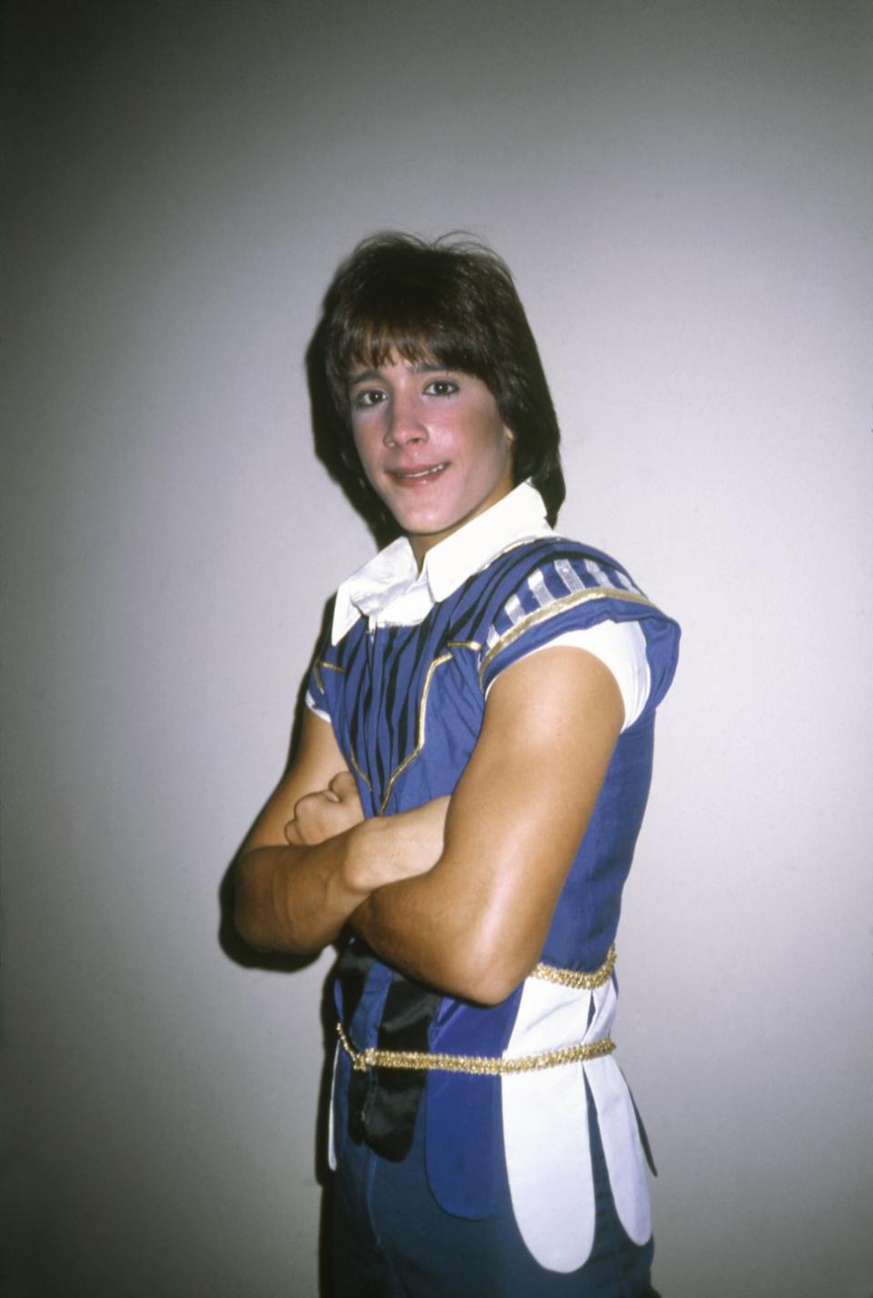 roy rossello wearing a blue sleeveless costume, folding his arms and smiling for the camera