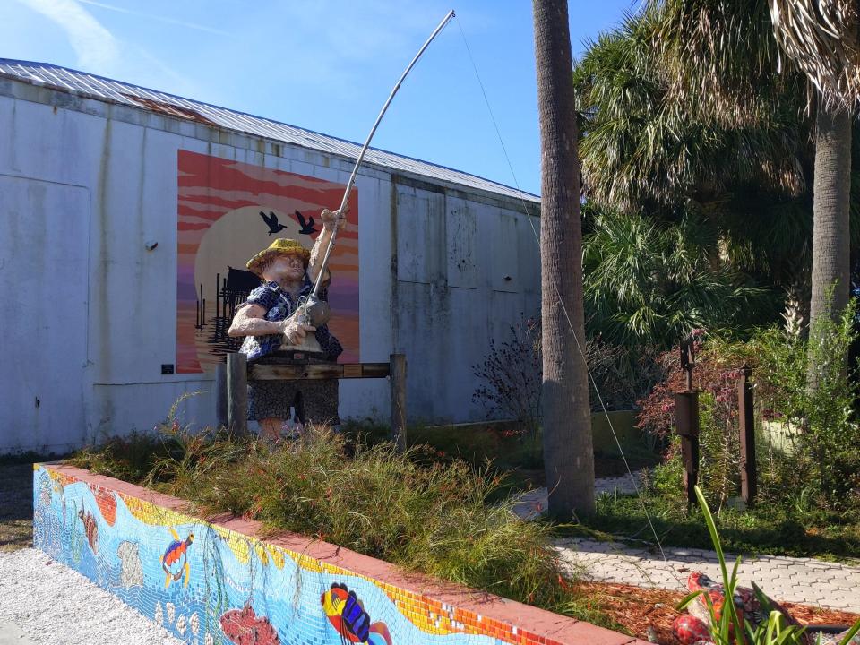 An art installation of a fisherman with a fishing pole extending out from it.