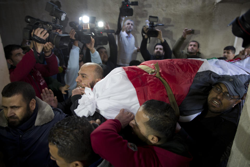 Mourners carry the body of Palestinian woman, Amal al-Taramsi, 43, who was killed by Israeli troops during Friday's protest at the Gaza Strip's border with Israel, into the family home during her funeral in Gaza City, Saturday, Jan. 12, 2019. (AP Photo/Khalil Hamra)