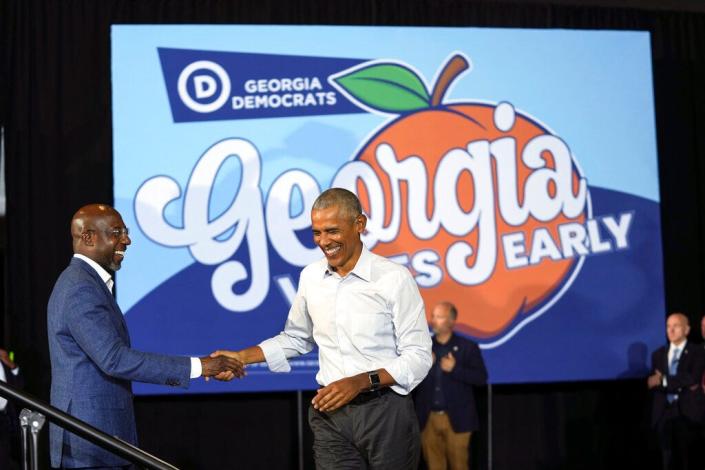 (right to left) Former President Barack Obama is greeted by Sen. Raphael Warnock of Georgia during a campaign rally in College Park, Georgia, on October 28, 2022.