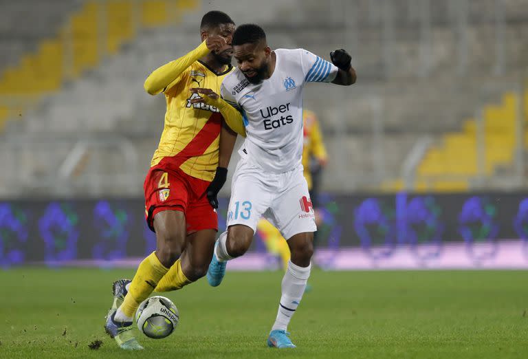 Cedric Bakambu, del Marsella, trata de llevarse el balón delante de Kevin Danso, de Lens, en un encuentro de la liga francesa, disputado el sábado 22 de enero de 2022 (AP Foto/Michel Spingler)