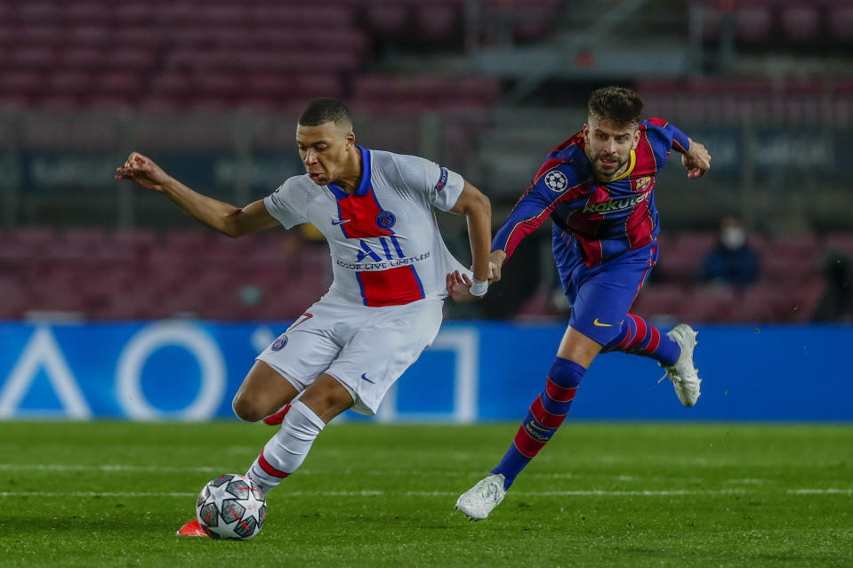 Gerard Piqué (derecha) del Barcelona jala de la camiseta a Kylian Mbappé del Paris Saint-Germain en el partido por los octavos de final de la Liga de Campeones, el martes 16 de febrero de 2021. (AP Foto/Joan Monfort)