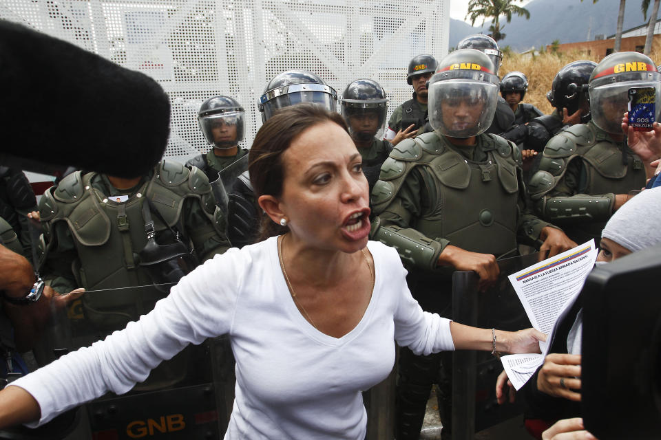 FILE - Opposition Congresswoman Maria Corina Machado speaks to the media and supporters in front of a line of Bolivarian National Guards during an anti-government march in Caracas, Venezuela, March 16, 2014. The government’s move to ban her from public office in 2023 has helped rally the fractured opposition and focus much-needed attention on their effort to hold an independent presidential primary election. (AP Photo/Esteban Felix, File)