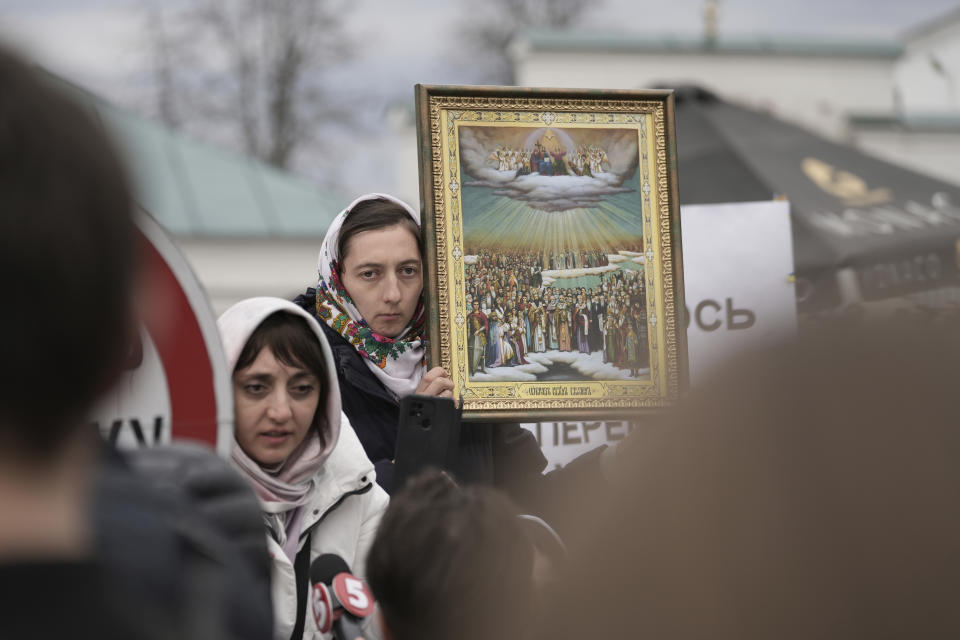 A supporter of Ukrainian Orthodox Church holds an icon outside the Kyiv Pechersk Lavra monastery complex in Kyiv, Ukraine, Saturday, April 1, 2023. In a bitter dispute over a famed Orthodox monastery, Ukraine's top security agency notified a leading priest on Saturday that he was suspected of justifying Russia's aggression, a criminal offense, Metropolitan Pavel, the abbot of the Kyiv-Pechersk Lavra monastery, Ukraine's most revered Orthodox site, has resisted the authorities' order to vacate the complex. Earlier in the week, he cursed Ukrainian President Volodymyr Zelenskyy, threatening him with damnation. (AP Photo/Roman Hrytsyna)