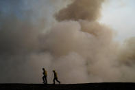 Two firefighters walk along the ridge as smoke from the Blue Ridge Fire rises Tuesday, Oct. 27, 2020, in Yorba Linda, Calif. Crews tried to beat back two out-of-control wildfires in Southern California on Tuesday that have kept tens of thousands of people out of their homes even as another round of dangerous fire weather raises the risk for flames erupting across the state. (AP Photo/Jae C. Hong)