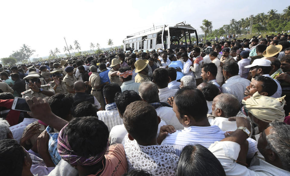 A crowd gathers around a bus that was retrieved after it fell into a canal in Mandya district in the southern Indian state of Karnataka, Saturday, Nov. 24, 2018. At least 25 people, many of them schoolchildren, were killed when a speeding bus fell into a canal in southern India on Saturday, an official and media reports said. (AP Photo/Madhusudhan Sr)