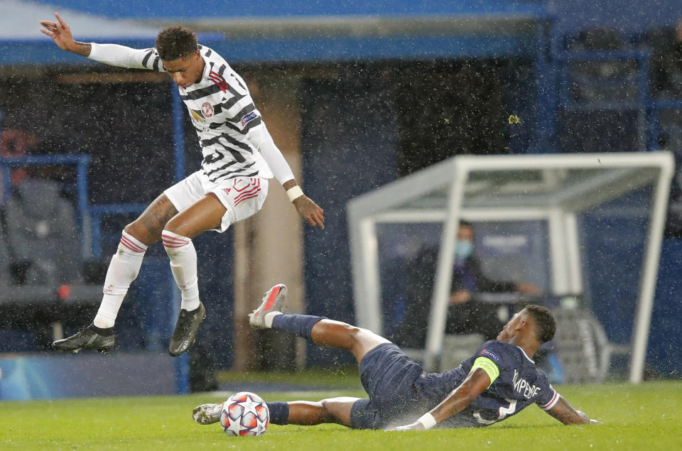 Manchester United's Marcus Rashford leaps over a challenge by PSG's Presnel Kimpembe during the Champions League group H soccer match between Paris Saint-Germain and Manchester United at the Parc des Princes in Paris, France, Tuesday, Oct. 20, 2020. (AP Photo/Michel Euler)