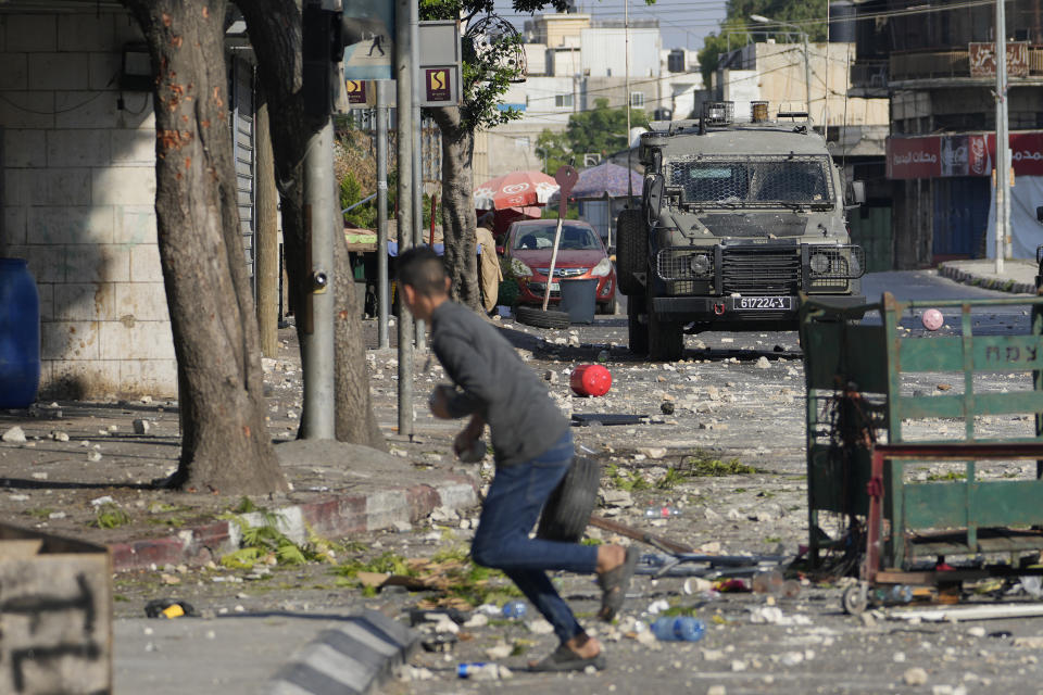 A Palestinian demonstrator holds rocks as the Israeli army carries out an operation in the West Bank town of Nablus, Tuesday, Aug. 9, 2022. (AP Photo/Majdi Mohammed)