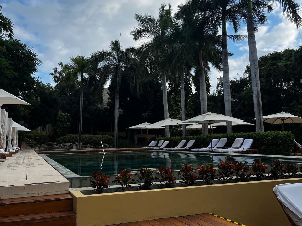 Resort pool surrounded by palm trees and white lounge chairs