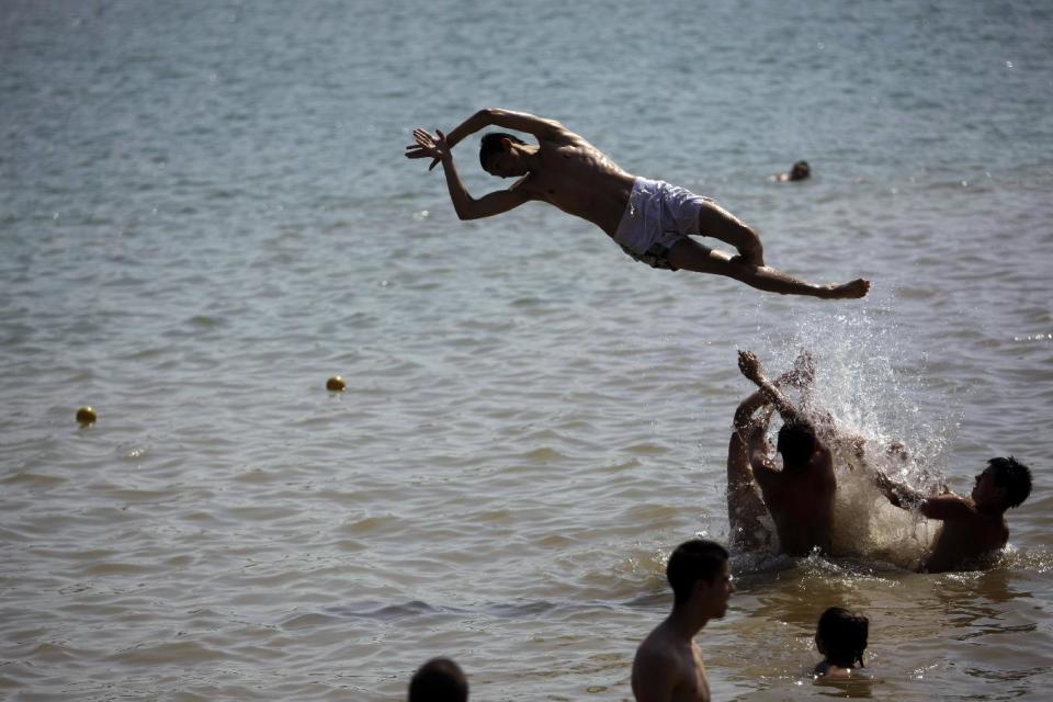 In this photo taken Thursday, June 20, 2013, a youth jumps into the waters of the Ada Ciganlija lake in Belgrade, Serbia. Belgrade today is known for nightlife, clubbing and a fun-loving lifestyle, but its past is scarred by war. An industrial zone by the Belgrade Fair then leads into Ada Ciganlija, a lake resort that is Belgrade’s favorite relaxation and picnic area. (AP Photo/ Marko Drobnjakovic)