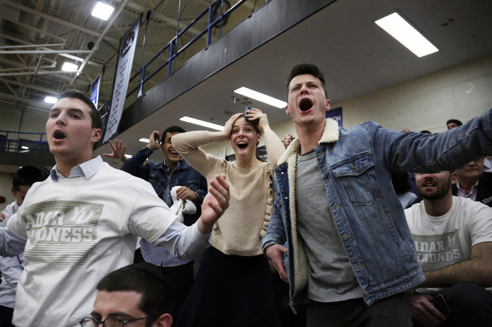 From left, Yeshiva University students Evan Goldman, Yosef Ajami and Tehilla Tiegman shout from the stands during the Skyline Conference men's basketball semifinal game between Yeshiva University and Farmingdale State College at Yeshiva University in New York, Feb. 27, 2020. (AP Photo/Jessie Wardarski)