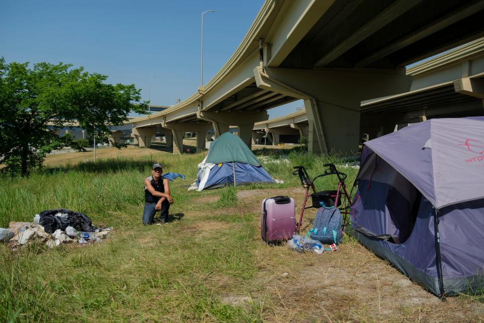 David James Porter kneels outside his tent under Interstate 794 in Milwaukee on Friday.