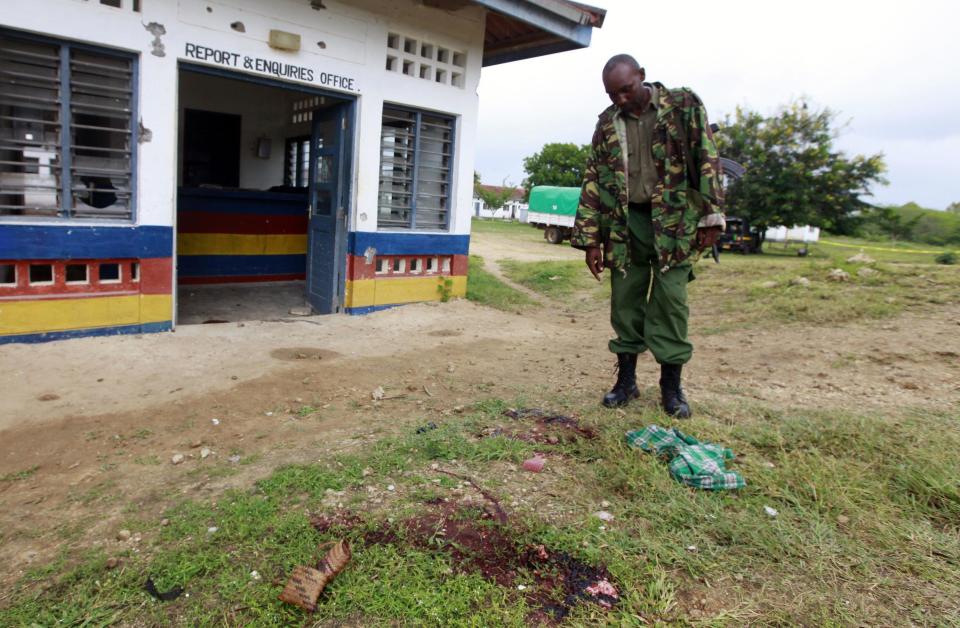 A policeman stands near a pool of blood where his colleague was killed during an attack at Gamba police station