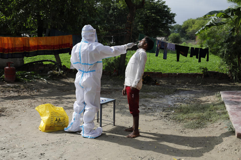 A health worker in protective suit takes a nasal swab sample of a man to test for COVID-19 in Kusehta village north of Prayagraj, India, Saturday, May 29, 2021. (AP Photo/Rajesh Kumar Singh)