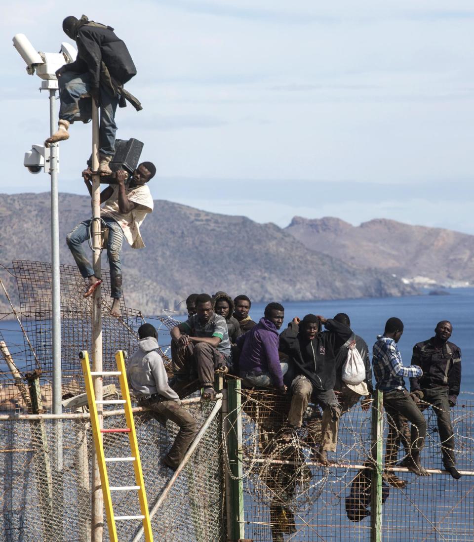 Sub-Saharan migrants sit on top of a metallic fence that divides Morocco and the Spanish enclave of Melilla on Thursday April 3, 2014. Spanish and Moroccan police have thwarted a fresh attempt by dozens of African migrants to try to scale border fences to enter the Spanish enclave of Melilla. Thousands of sub-Saharan migrants seeking a better life in Europe are living illegally in Morocco and regularly try to enter Melilla in the hope of later making it to mainland Spain. (AP Photo/Santi Palacios)