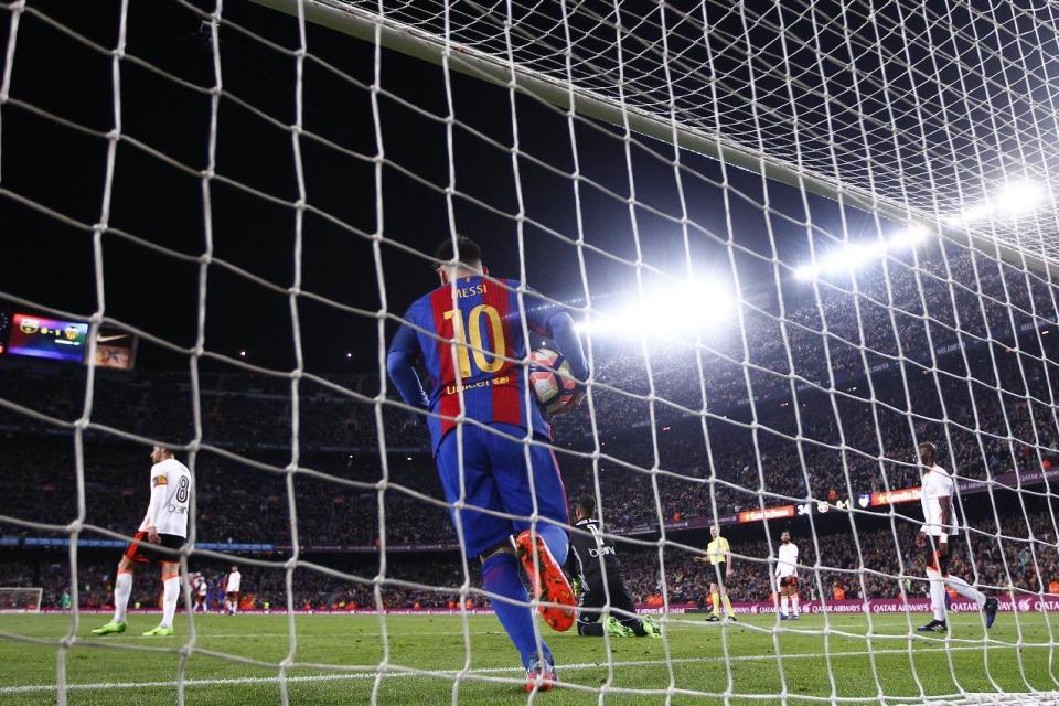 El argentino Lionel Messi, del Barcelona, recoge el balón de entre las redes tras un gol de su compañero Luis Suárez, en el partido de liga disputado el domingo 19 de marzo de 2017 ante Valencia (AP Foto/Manu Fernández)