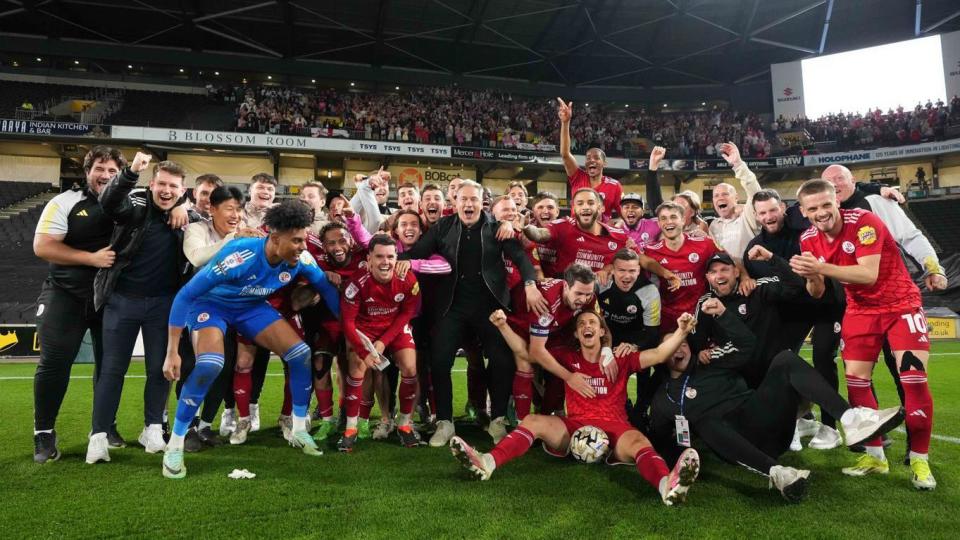 Crawley Town's playing squad and management celebrate in front of their fan at Stadium MK