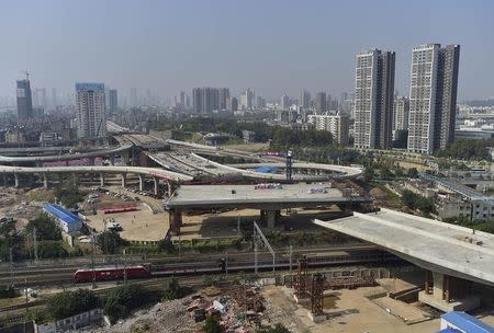 An overpass is seen under construction as a train travels past in Wuhan, Hubei province, October 24, 2014. REUTERS/Stringer/Files