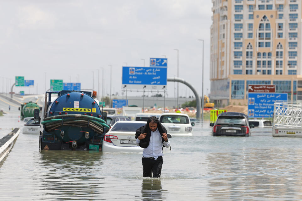 A driver walks along a flooded highway after a rainstorm in Dubai, United Arab Emirates, on Wednesday, April 17, 2024.  / Credit: Christopher Pike/Bloomberg via Getty Images