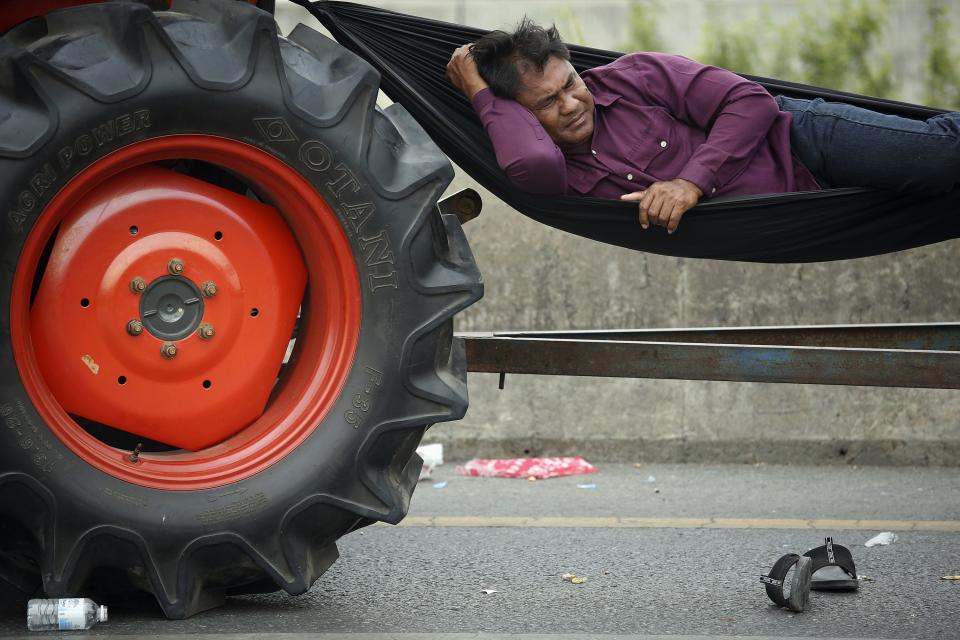 A rice farmer sleeps in a hammock attached to his tractor on a highway where farmers spent a night in Ayutthaya province February 21, 2014. Thai farmers called off a tractor drive to Bangkok's main airport to protest against not being paid under a rice subsidy scheme after an assurance they would get their money, a spokesman said, welcome news for Prime Minister Yingluck Shinawatra. REUTERS/Damir Sagolj (THAILAND - Tags: AGRICULTURE CIVIL UNREST POLITICS SOCIETY)