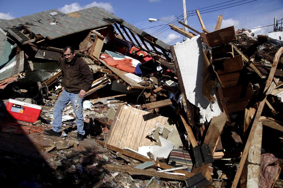 James Traina climbs over the remains of his parent's house which was destroyed by Superstorm Sandy in Staten Island, N.Y. Friday, Nov. 2, 2012. Mayor Michael Bloomberg has come under fire for pressing ahead with the New York City Marathon. Some New Yorkers say holding the 26.2-mile race would be insensitive and divert police and other important resources when many are still suffering from Superstorm Sandy. The course runs from the Verrazano-Narrows Bridge on hard-hit Staten Island to Central Park, sending runners through all five boroughs. The course will not be changed, since there was little damage along the route. (AP Photo/Seth Wenig)