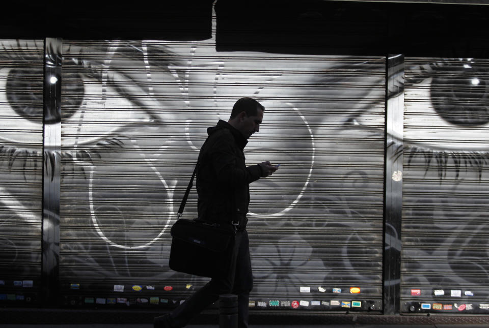 FILE - In this Thursday, Oct. 31, 2013, file photo, a man looks at his cellphone as he walks on the street in downtown Madrid. The National Security Agency has implanted software in nearly 100,000 computers around the world — but not in the United States — that allows the U.S. to conduct surveillance on those machines, The New York Times reported Tuesday, Jan. 14, 2014. (AP Photo/Francisco Seco, File)