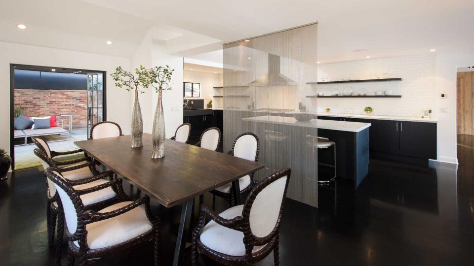 <p>The kitchen's black-and-white theme carries into the dining area, which is separated with a translucent screen that feels as much '80s disco as dining at home. </p>