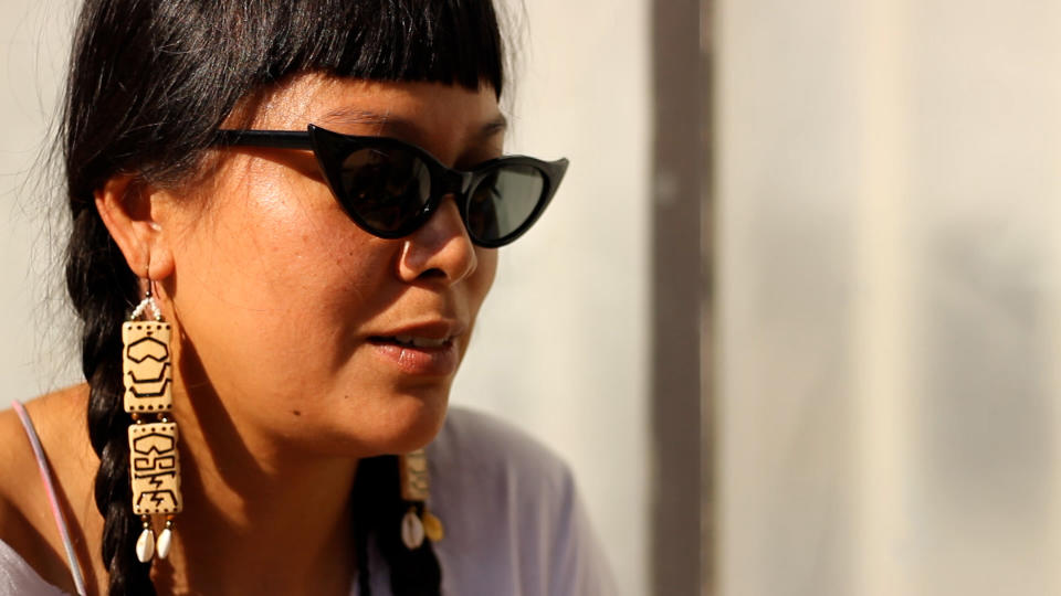 In Los Angeles, Diane Valencia shows off handmade earrings with a Baybayin inscription she created by burning wood. (Jordan Winters)