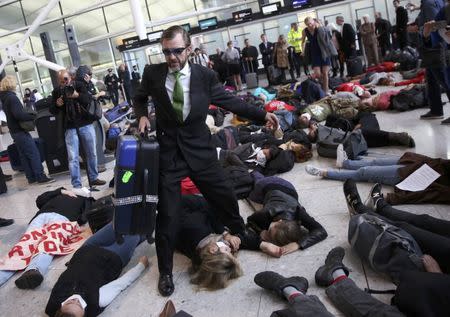 Climate activist group Reclaim the Power lie on the ground and carry luggage during a protest against airport expansion plans at Heathrow Airport in London, Britain October 1, 2016. REUTERS/Neil Hall