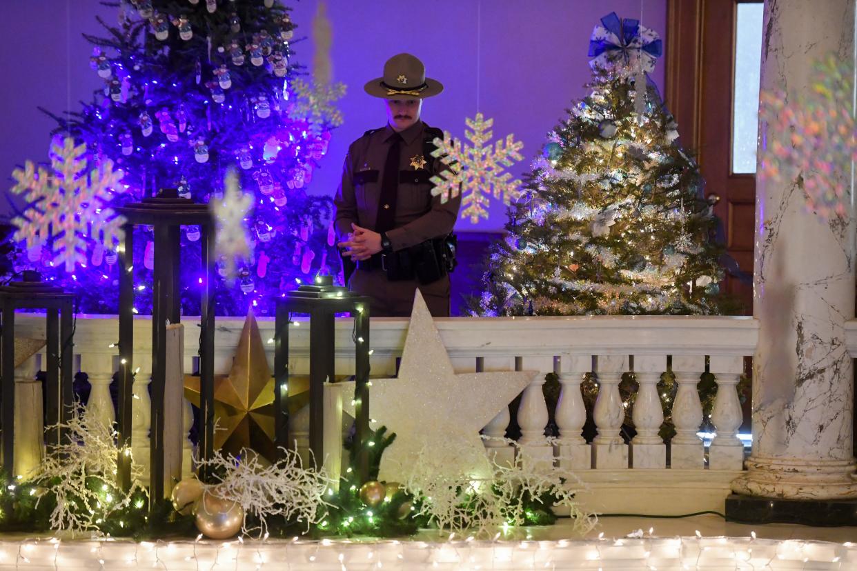 A state capitol officer stands near the decorated balcony to listen to the carolers on Tuesday, Dec. 5, 2023 at the South Dakota State Capitol in Pierre.