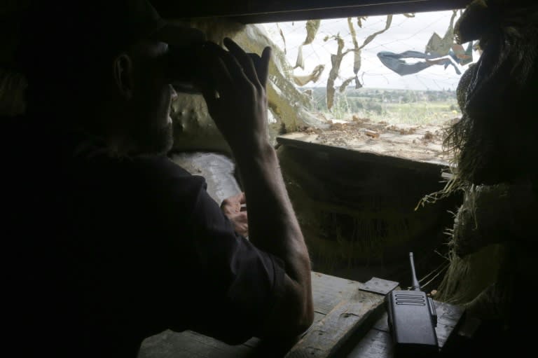 A Ukrainian serviceman looks through binoculars inside a fortified position near the front line with the pro-Russian seperatists in the village of Shyrokyne, Donetsk region, on June 29, 2015