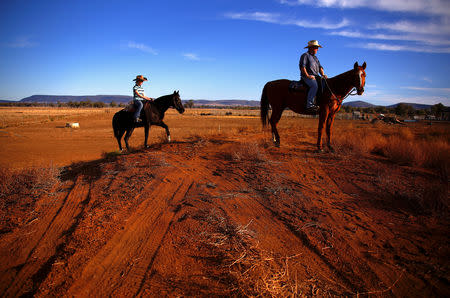 Farmer Scott Cooper and his daughter Charlie ride their horses along a fence in a drought-effected paddock on their property named "Nundah" located south of the central New South Wales town of Gunnedah in Australia, July 21, 2018. REUTERS/David Gray/Files