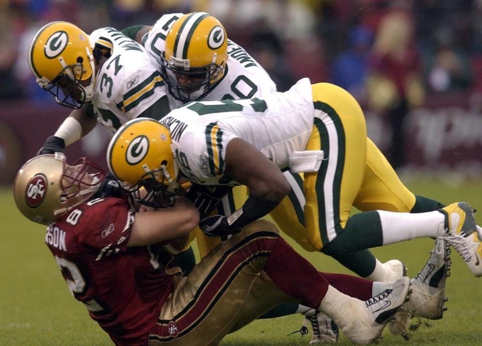 San Francisco 49ers tight end Eric Johnson is drilled by Green Bay Packers Tyrone Williams, Hardy Nickerson and Marques Anderson.