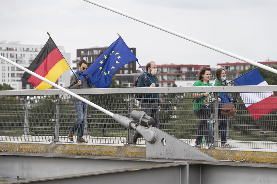 Members of pro-European French and German associations walk on a footbridge over the Rhine river and linking France to Germany, Sunday June 14, 2020 in Strasbourg, eastern France. The majority of European countries will be reopening Monday June 15, 2020 their borders and lifting the restrictions that had been in place during the COVID-19 pandemic. (AP Photo/Jean-Francois Badias)