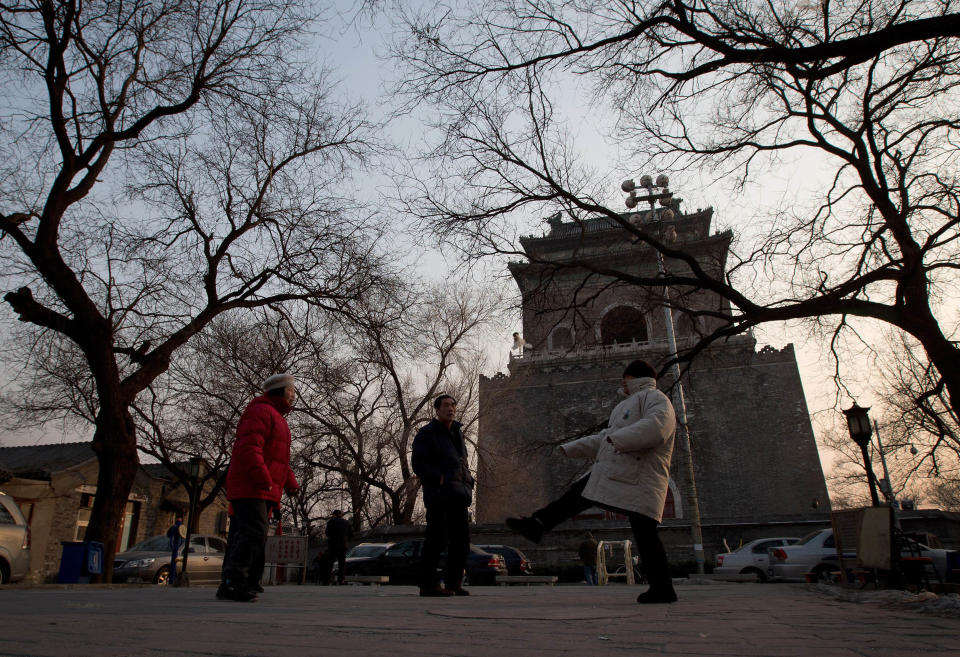 In this photo taken on Dec. 26, 2012, resident plays Jianzi, a Chinese traditional game at the square near the historical Drum and Bell Tower, seen in the background, in Beijing. The district government wants to demolish scuffed courtyard homes, move their occupants to bigger apartments farther from the city center and redevelop a square in 18th century Qing Dynasty fashion.(AP Photo/Andy Wong)