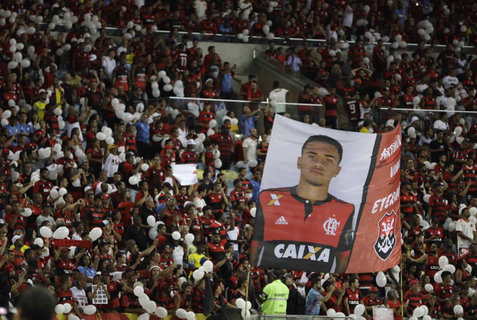 Fans hold up a banner that shows Arthur Vinicius, one of the 10 teenage players killed by a fire at the Flamengo training center last Friday, during a homage to the boys ahead of a soccer match between Flamengo and Fluminense, at the Maracana Stadium, in Rio de Janeiro, Brazil, Thursday, Feb. 14, 2019. (AP Photo/Leo Correa)