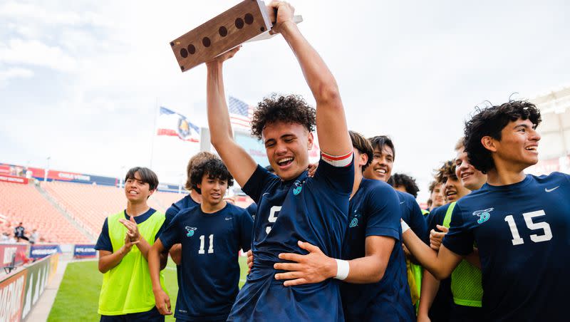 Juan Diego Catholic’s Hauroa Morgant (9) holds up the trophy after winning the 3A boys soccer state championship game at America First Field in Sandy on May 12, 2023.