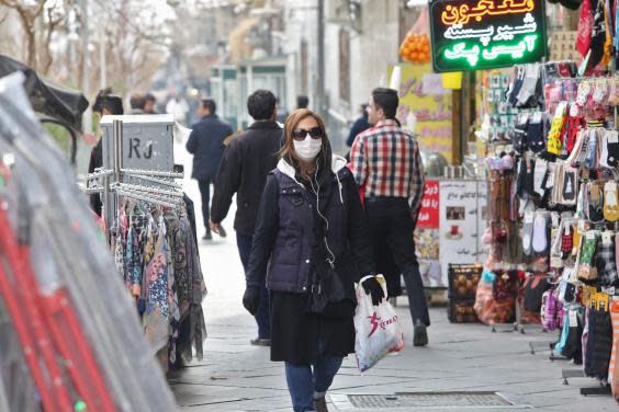 Woman wears protective mask while walking along the side of a street in the Iranian capital Tehran (AFP via Getty Images)