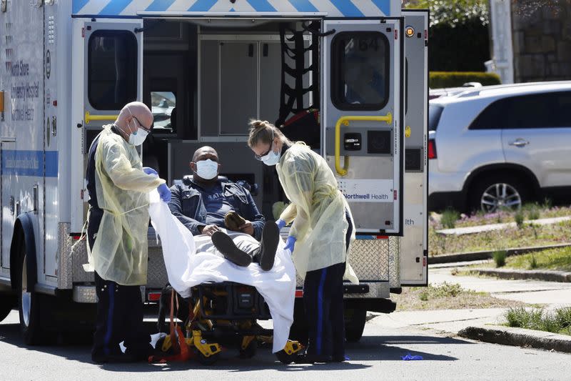 Emergency Medical Technicians (EMT) lift a patient that was identified to have coronavirus disease (COVID-19) into an ambulance while wearing protective gear, as the outbreak of coronavirus disease (COVID-19) continues, in New York City, New York