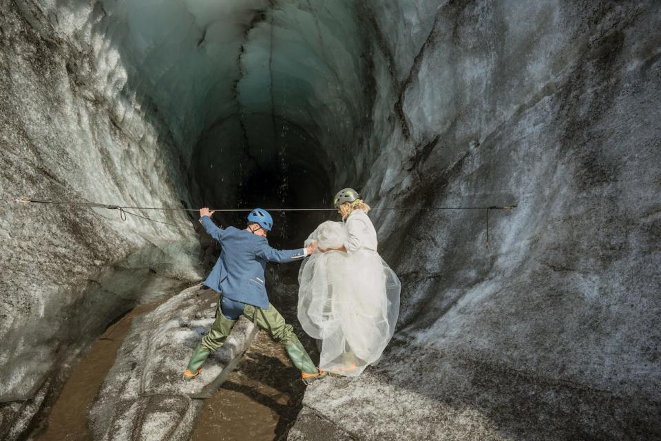 A bride and groom enter an ice cave in Iceland.
