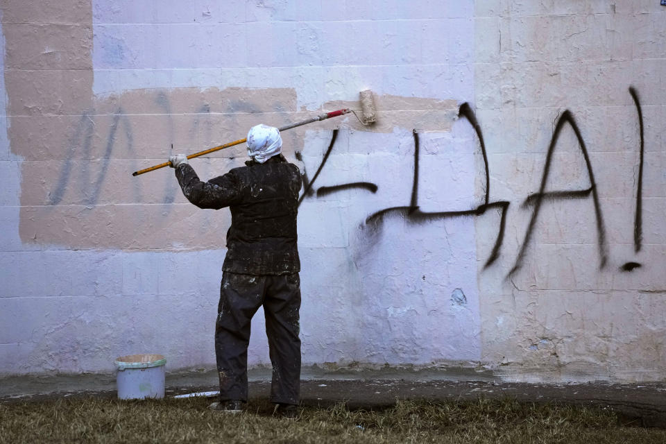 FILE - A worker paints over graffiti saying 'Yes to Peace!' on a wall of an apartment building in St. Petersburg, Russia, Friday, March 18, 2022. (AP Photo, File)