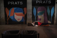 A homeless man sleeps on a street in downtown Barcelona, Spain, late Friday, March 5, 2021. According to reports, poverty have increased considerably in the last months as Spain has been in lockdown to fight the coronavirus pandemic. (AP Photo/Emilio Morenatti)