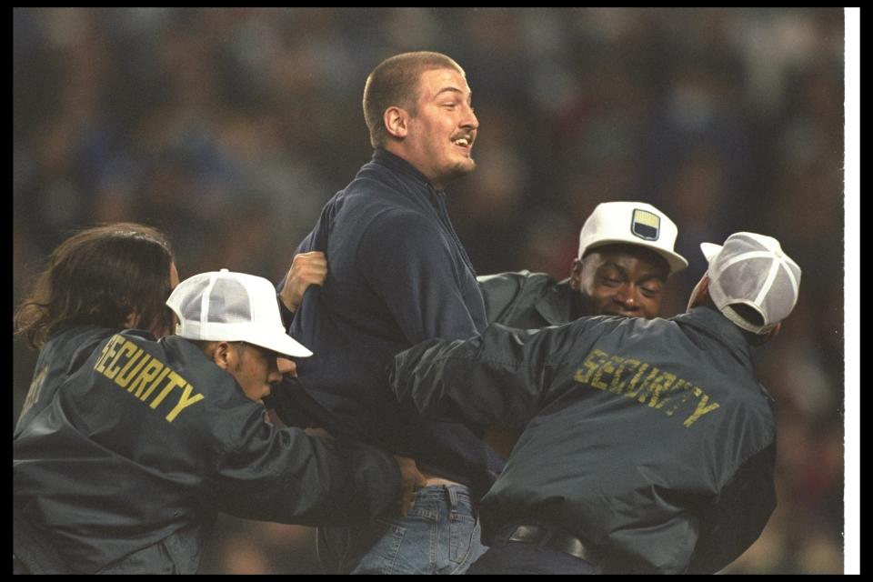 Security officers apprehend a fan who ran onto the field during Game Two of the World Series between the New York Yankees and the Atlanta Braves at Yankee Stadium in New York City, New York. The Braves won the game, 4-0.