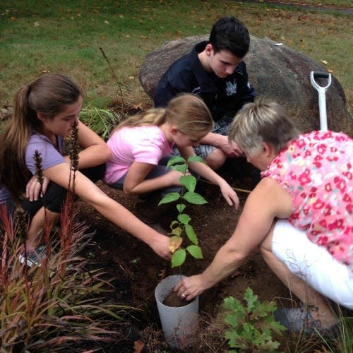 Family members plant a tree with the Living Urn containing ashes of a loved one to create a living memorial.