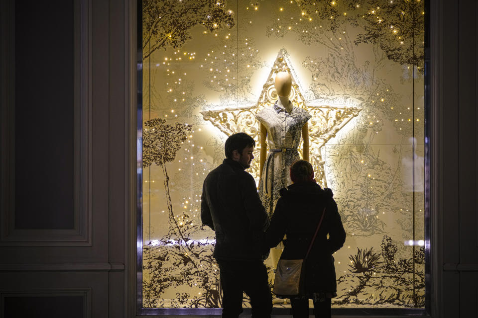 A couple stops in front of a shop window in Vienna, Austria, Saturday, Nov. 20, 2021. The Austrian government announced a nationwide lockdown that will start Monday and comes as average daily deaths have tripled in recent weeks and hospitals in heavily hit states have warned that intensive care units are reaching capacity. (AP Photo/Vadim Ghirda)