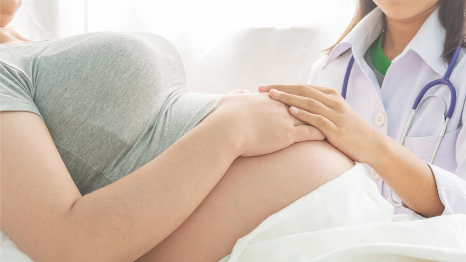 A medical provider examines a pregnant woman.