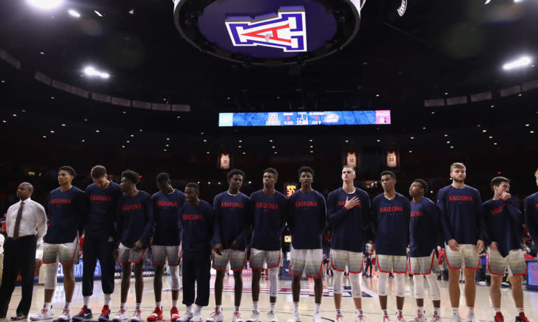 The Arizona Wildcats basketball team standing during the National Anthem.