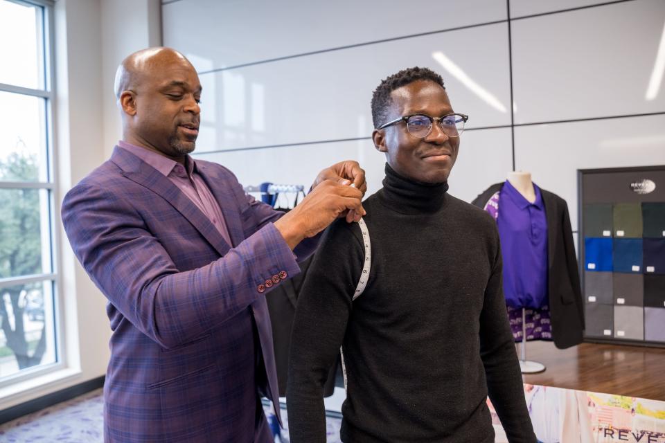 Carlton Dixon, owner of Reveal Suits, measures Texas Christian University student Milton Mondlane for a custom suit. More colleges are providing students with professional attire for networking events and job interviews.