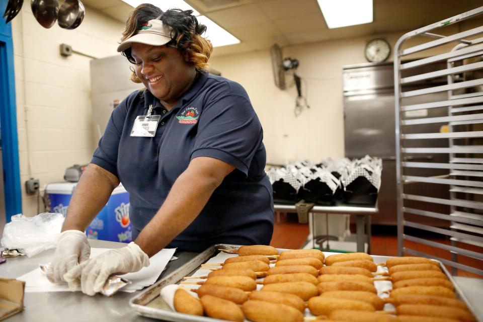 Natalye Mulberry, a food service specialist with the Alachua County School Board Food and Nutrition Department, prepare corndogs as part of the summer meal program at Buchholz High School cafeteria on June 27, 2017. The school district will again provide free meals during the summer to children 18 and younger.  [Brad McClenny/Special to The Guardian]